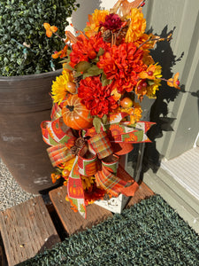 View from the Front of a Lantern Swag with Fall Leaves of Brown, Yellow and Orange, with Orange and Yellow Mums, Pumpkins , Cinnamon Sticks, Red Berries and Pine Cones on a White Lantern on the Porch