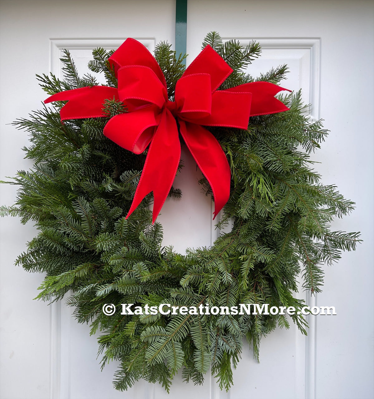 Picture of Fresh Evergreen Wreath with a Velvet Red Bow on a White Door