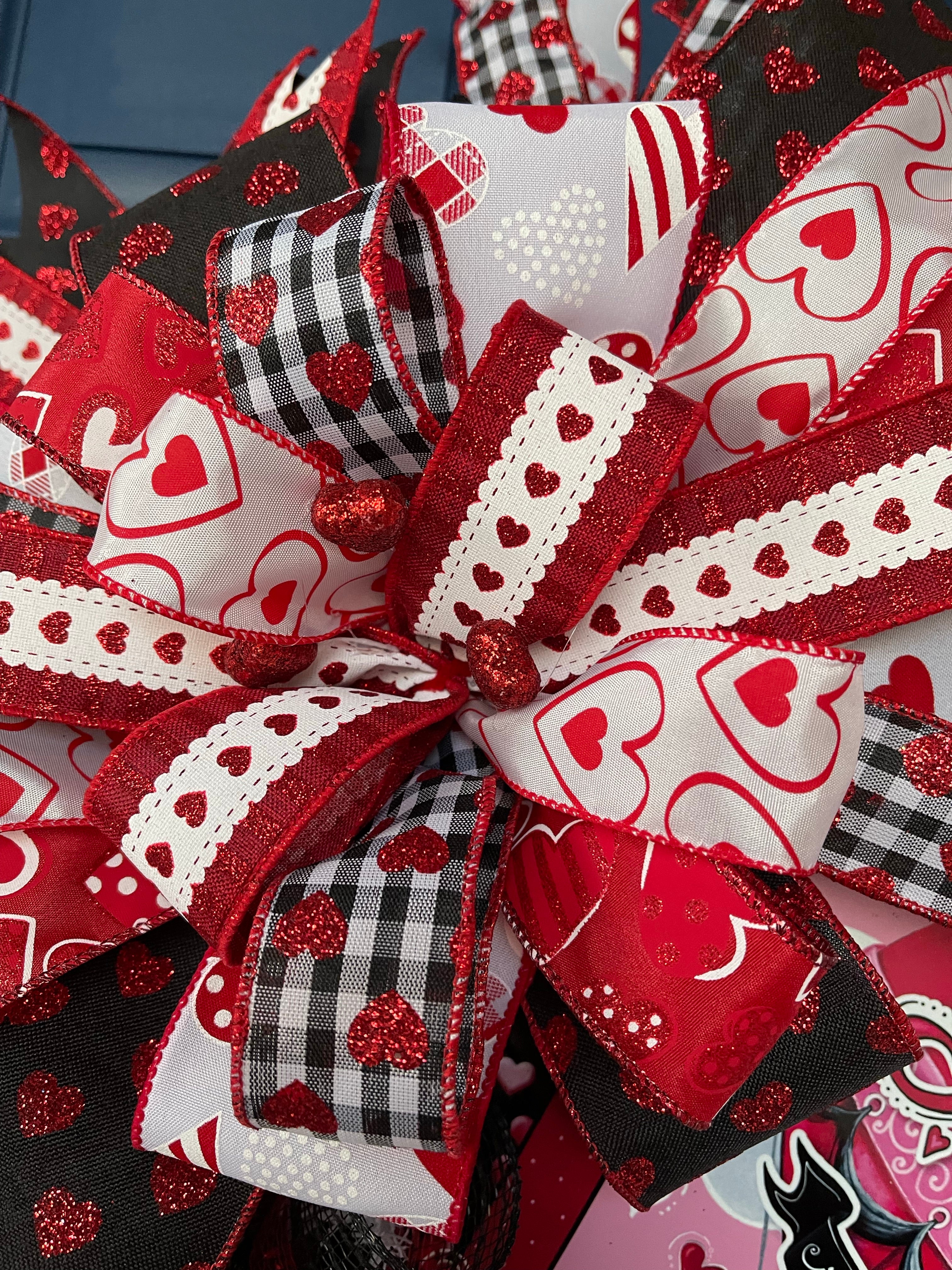Close Up Detail of Bow featuring ribbons of Red, White and Black with Hearts with Red Glitter Hearts in the Center