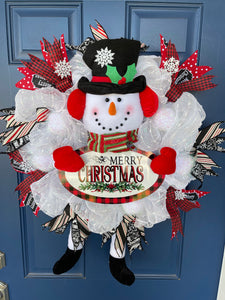 Red, White and Black Snowman Plush Deco Mesh Wreath holding a Merry Christmas Sign on a blue door