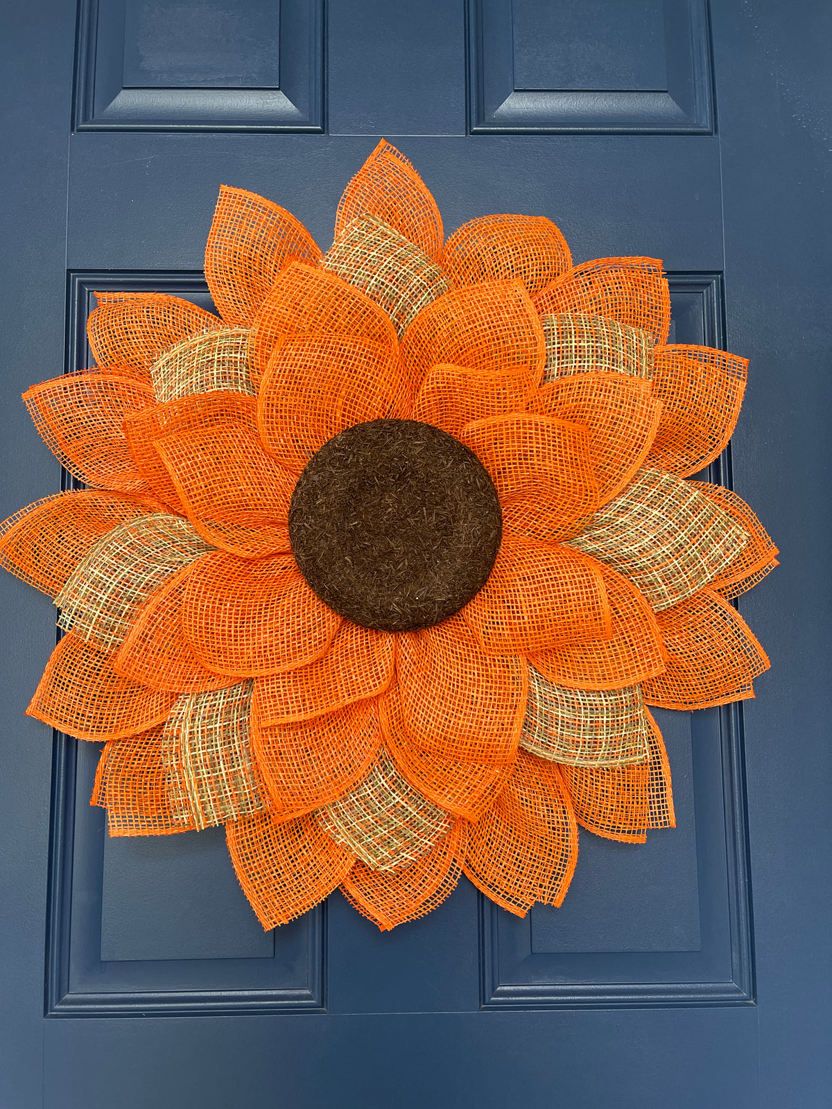 Bottom View Looking Up of Poly Burlap Mesh Sunflower Wreath Featuring Orange and Patterned Colors of Yellow, Brown and Orange with a Brown Center on a Blue Door