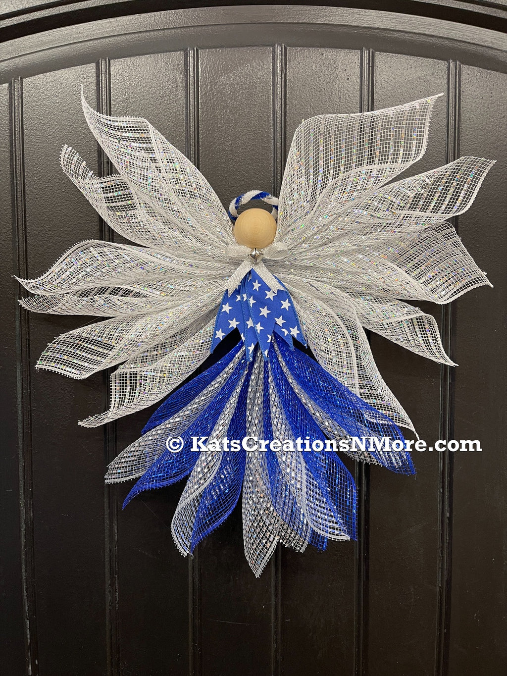 Blue, white and silver deco mesh angel with blue ribbon with white stars, wooden head, silver bow and bell with blue and white halo on a black door. 