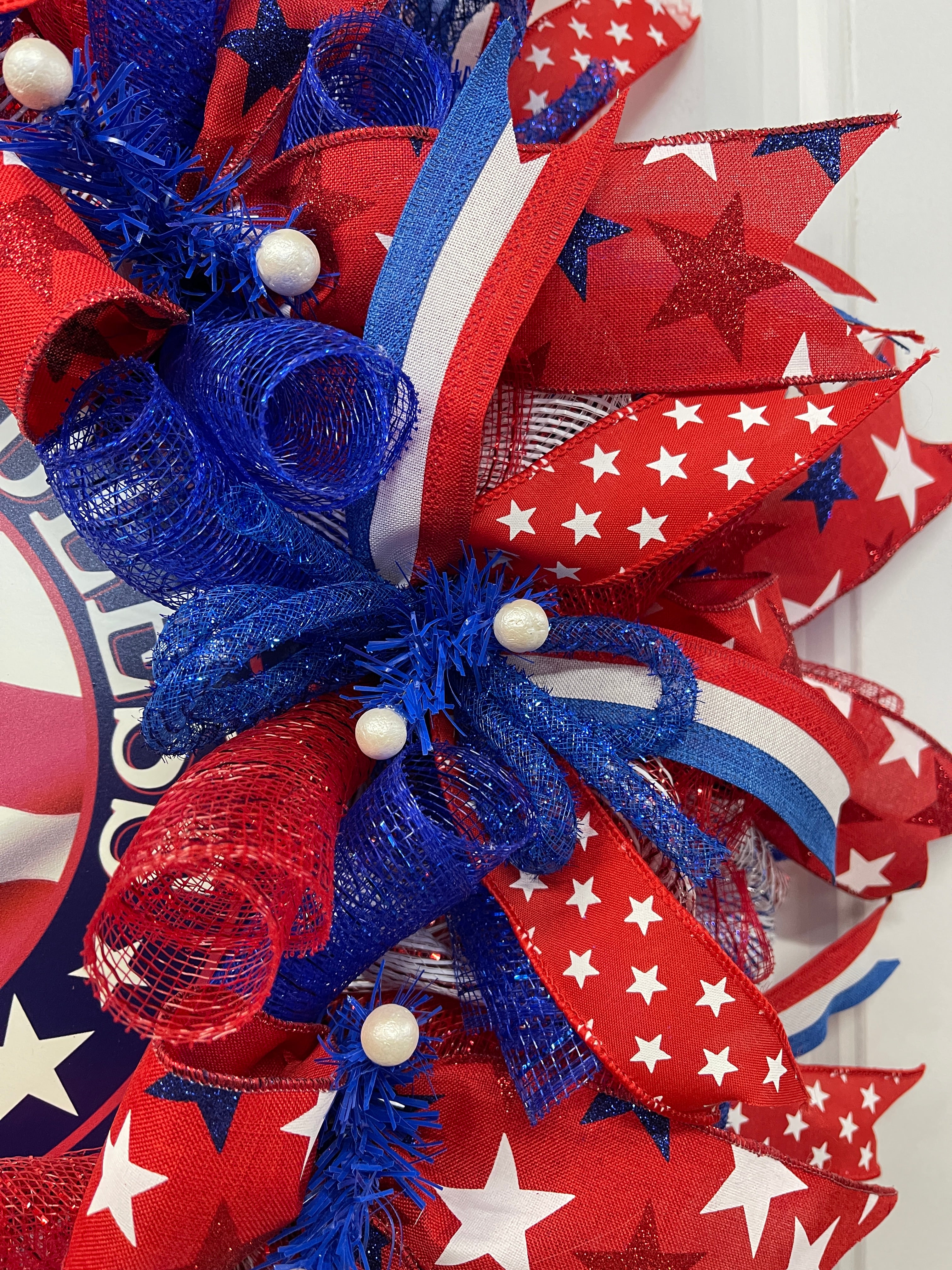 Close Up Detail of Blue Tinsel Tubing, White Balls and Ribbon tails with red, white and blue stripes and white stars on red ribbon