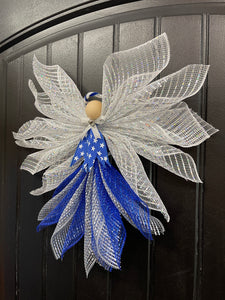 Right Side View of Blue, white and silver deco mesh angel with blue ribbon with white stars, wooden head, silver bow and bell with blue and white halo on a black door. 