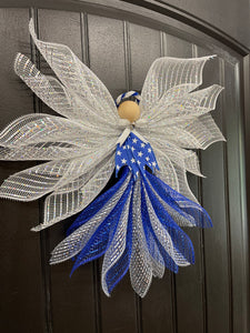 Left Side View of Blue, white and silver deco mesh angel with blue ribbon with white stars, wooden head, silver bow and bell with blue and white halo on a black door. 