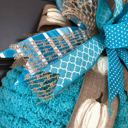 Close Up of Bow on Pumpkin Wreath, featuring Blue, White and Tan Ribbons.