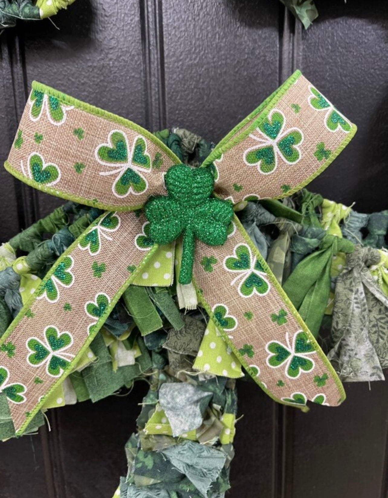 Close up of Detail on Ribbon featuring green shamrocks on beige with a glittered green clover in the center