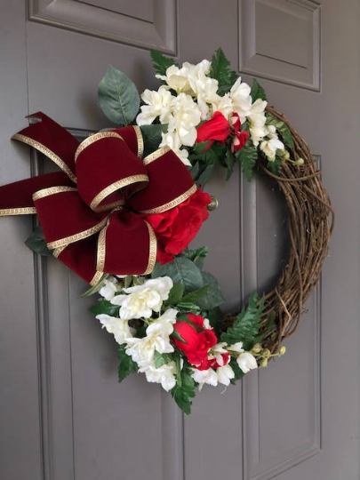 Left Side View of Red Rose and White Delphinium Floral Grapevine and Fern Wreath with Gold and Red Velvet Bow on a Gray Door