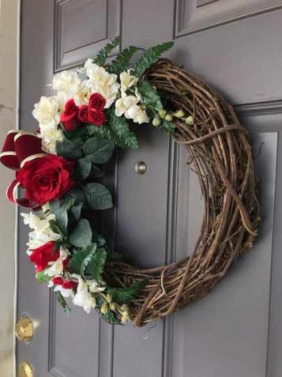 Right Side View of Red Rose and White Delphinium Floral Grapevine and Fern Wreath with Gold and Red Velvet Bow on a Gray Door