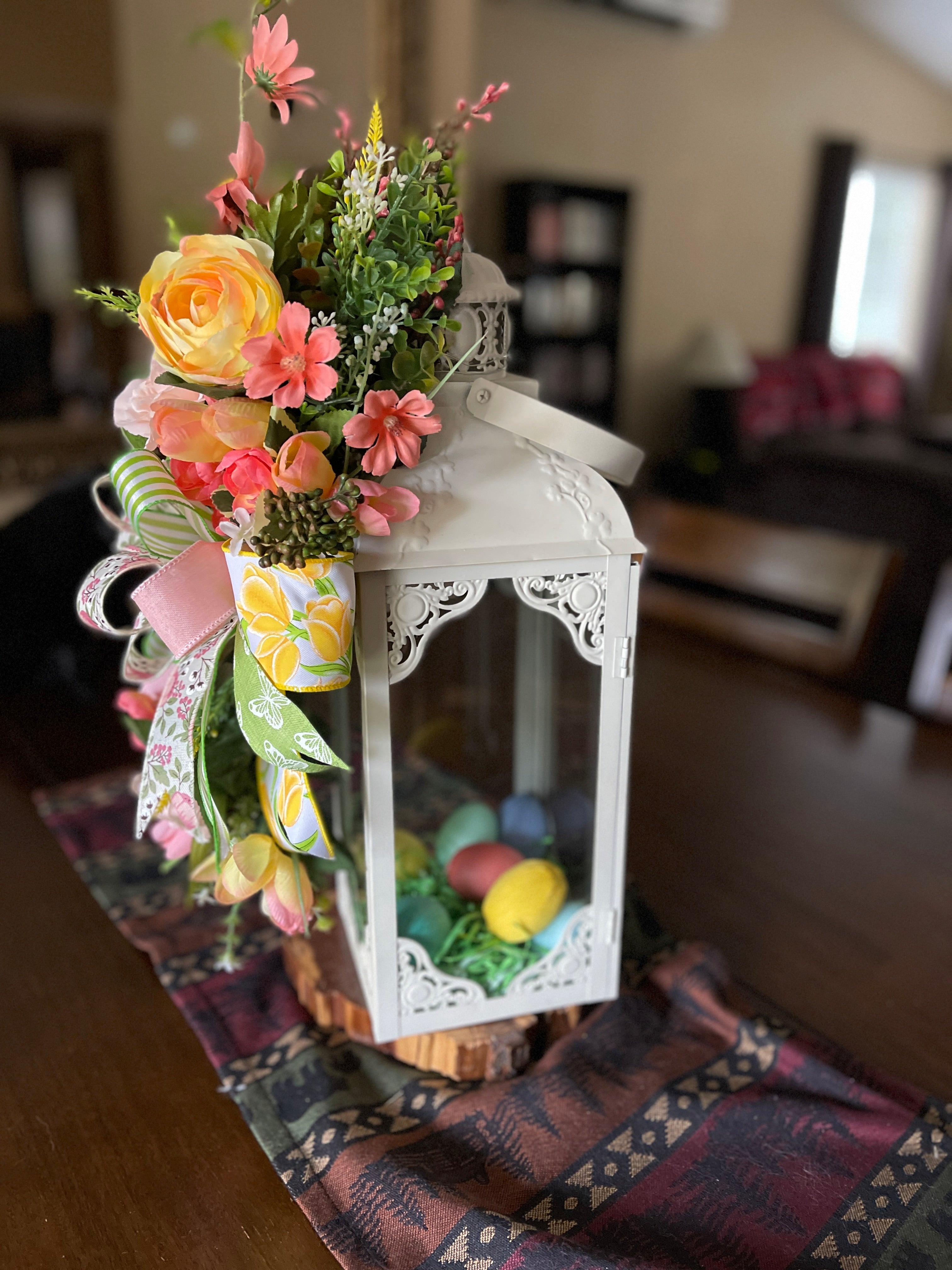 Side View of Pastel Green, Yellow, Peach and Pink Ranunculus, Tulips, Poppies and Roses along with Meadow Flowers  with a Bow Swag on a White Lantern