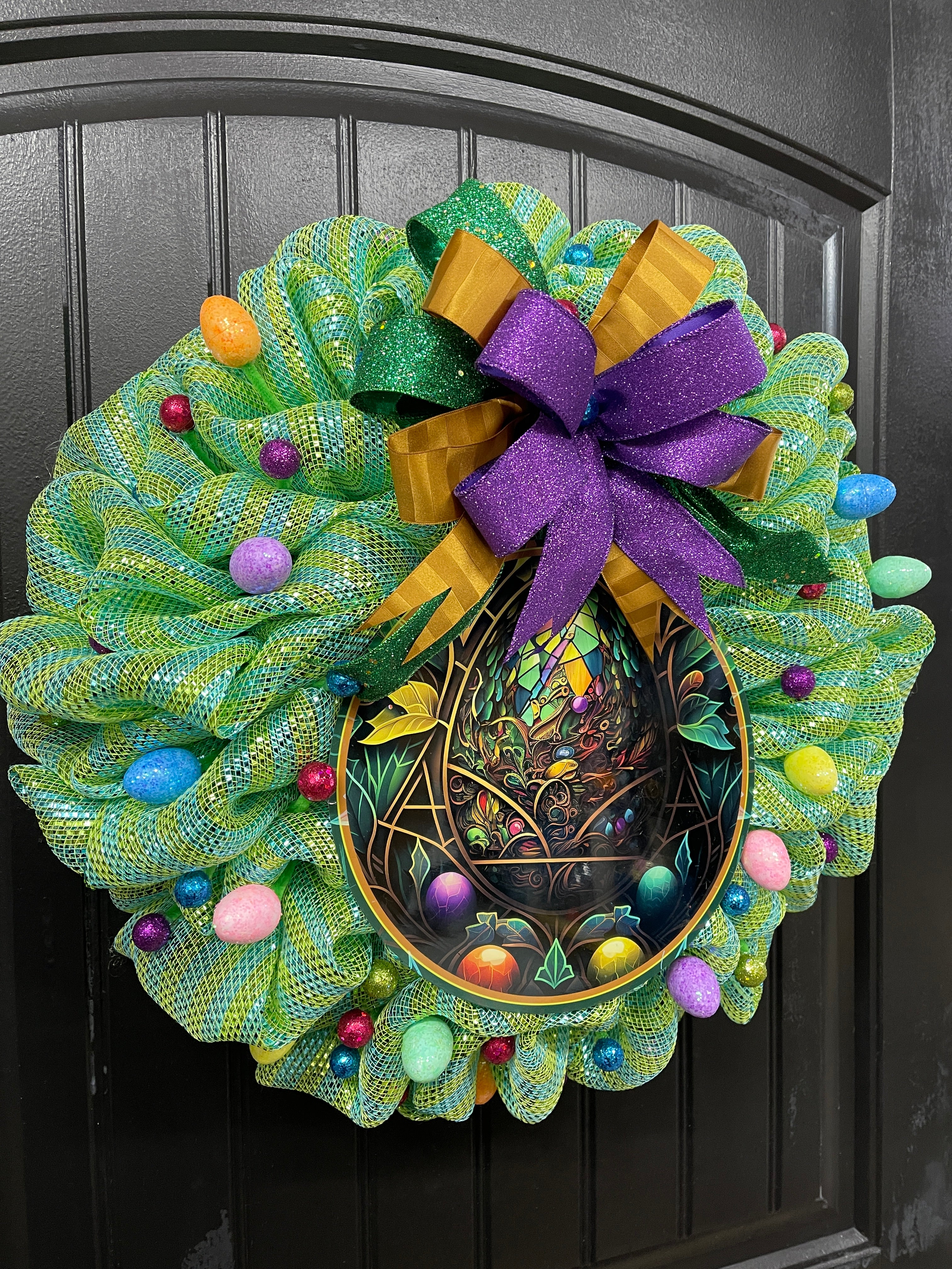 Left Side View of Stained Glass Look Easter Egg Bubble Deco mesh Wreath with a Bow with Glitter Balls and Eggs on a Black Door