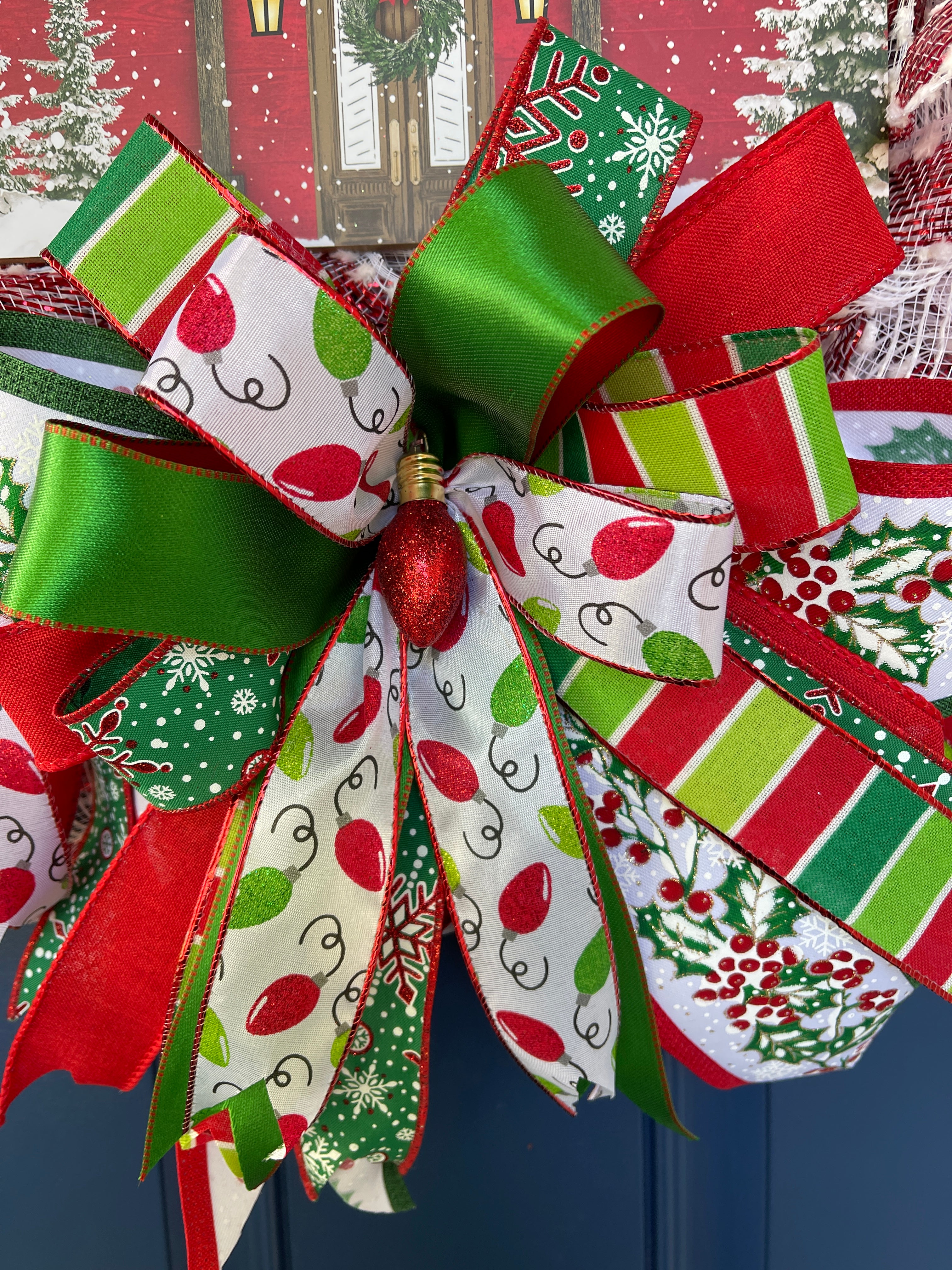 Close Up of Bow featuring a Colored Red Christmas Bulb in the Center with Red, White and Green Ribbons