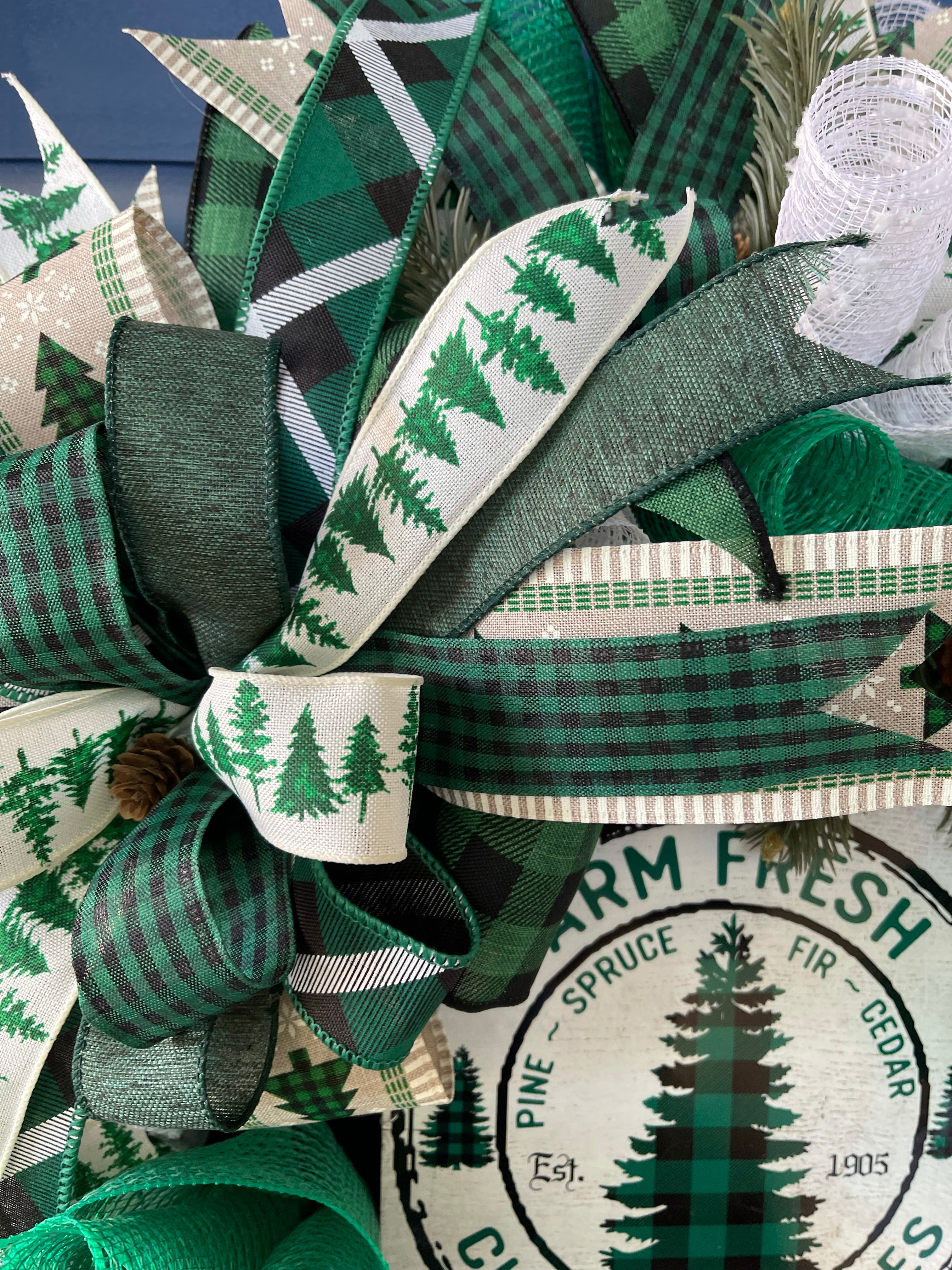 Close Up of Ribbons in the Bow featuring pine trees on white, along with various prints of black, white and Green plaid and gingham ribbons