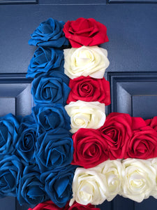 Close up Detail of Red, White and Blue Roses in the shape of a cross on a blue door