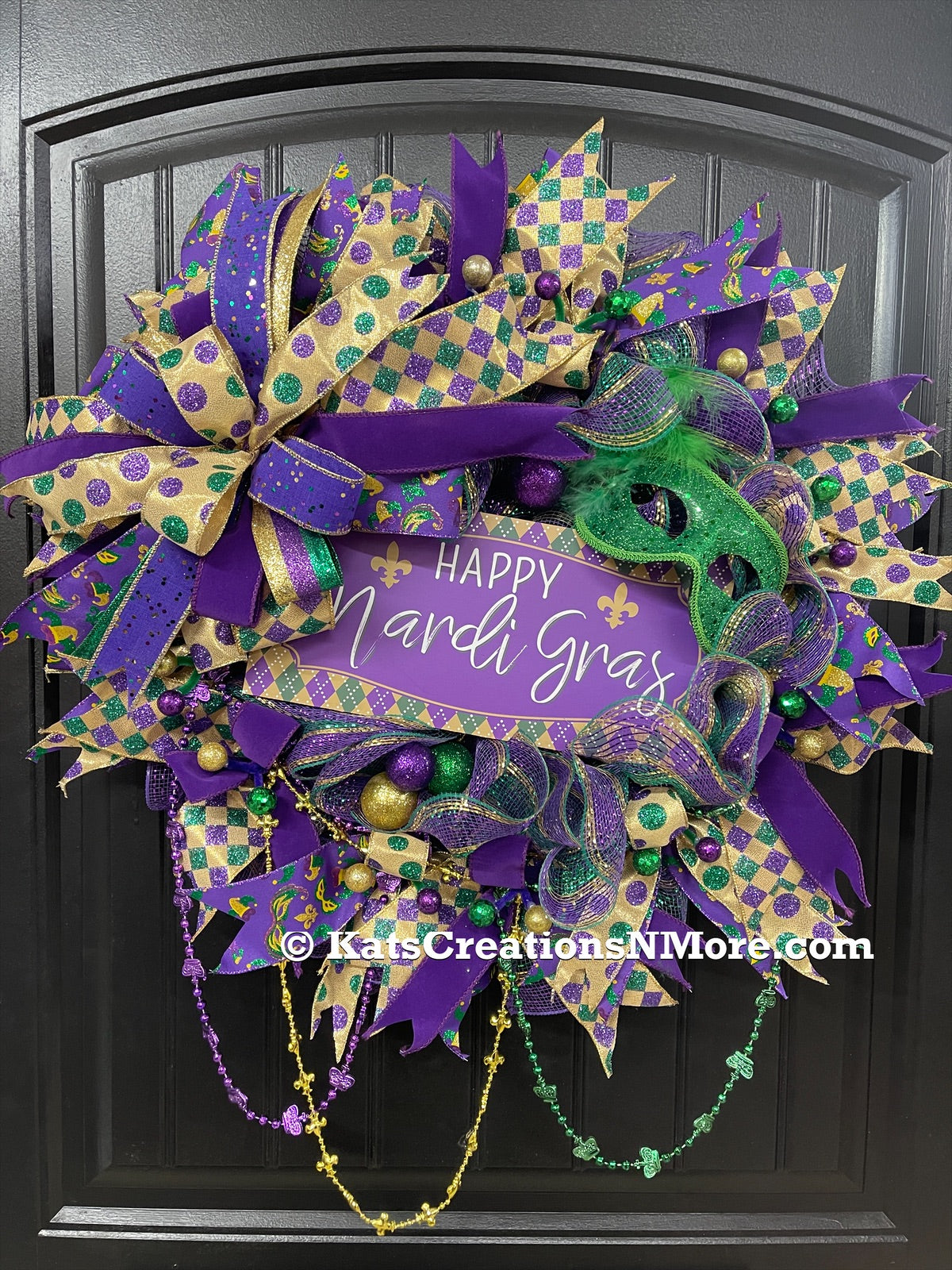 Purple, Green and Gold Mardi Gras Wreath with Beads, Balls, Mask and Bow on a Black Door