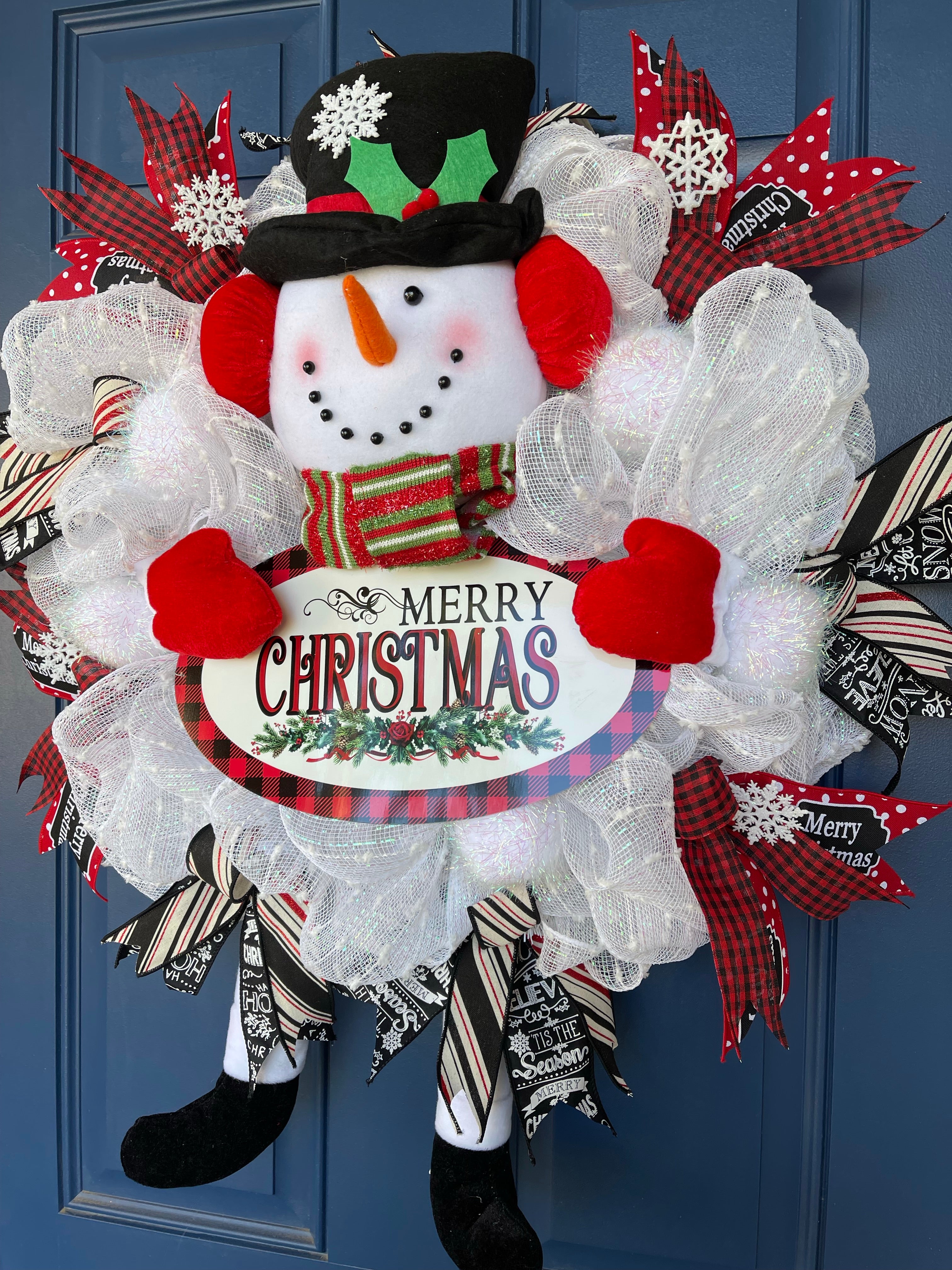Right Side View of Red, White and Black Snowman Plush Deco Mesh Wreath holding a Merry Christmas Sign on a blue door