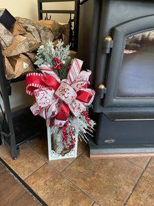 Red and White Candy Cane and Peppermint Lantern Swag with Evergreen Florals and Red Berries used on a lantern placed on a fireplace area. 