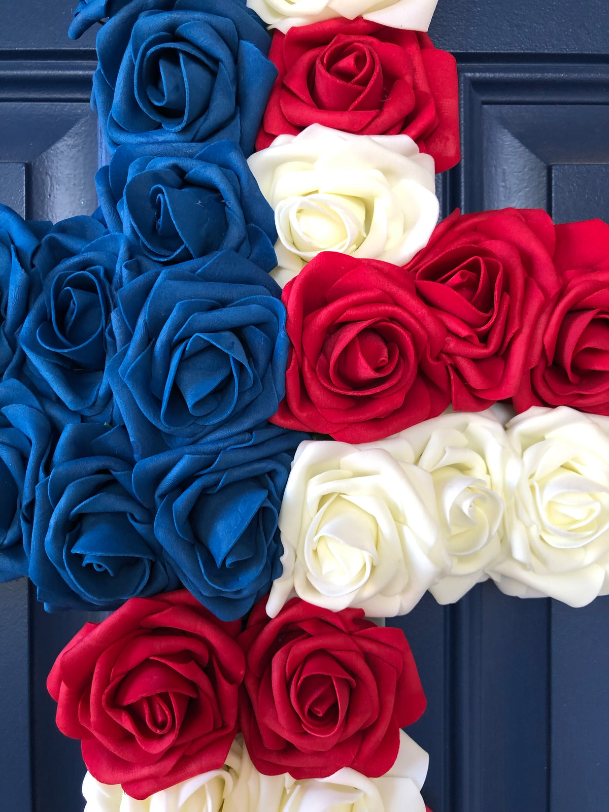 Red, White and Blue Roses in the shape of a cross on a blue door