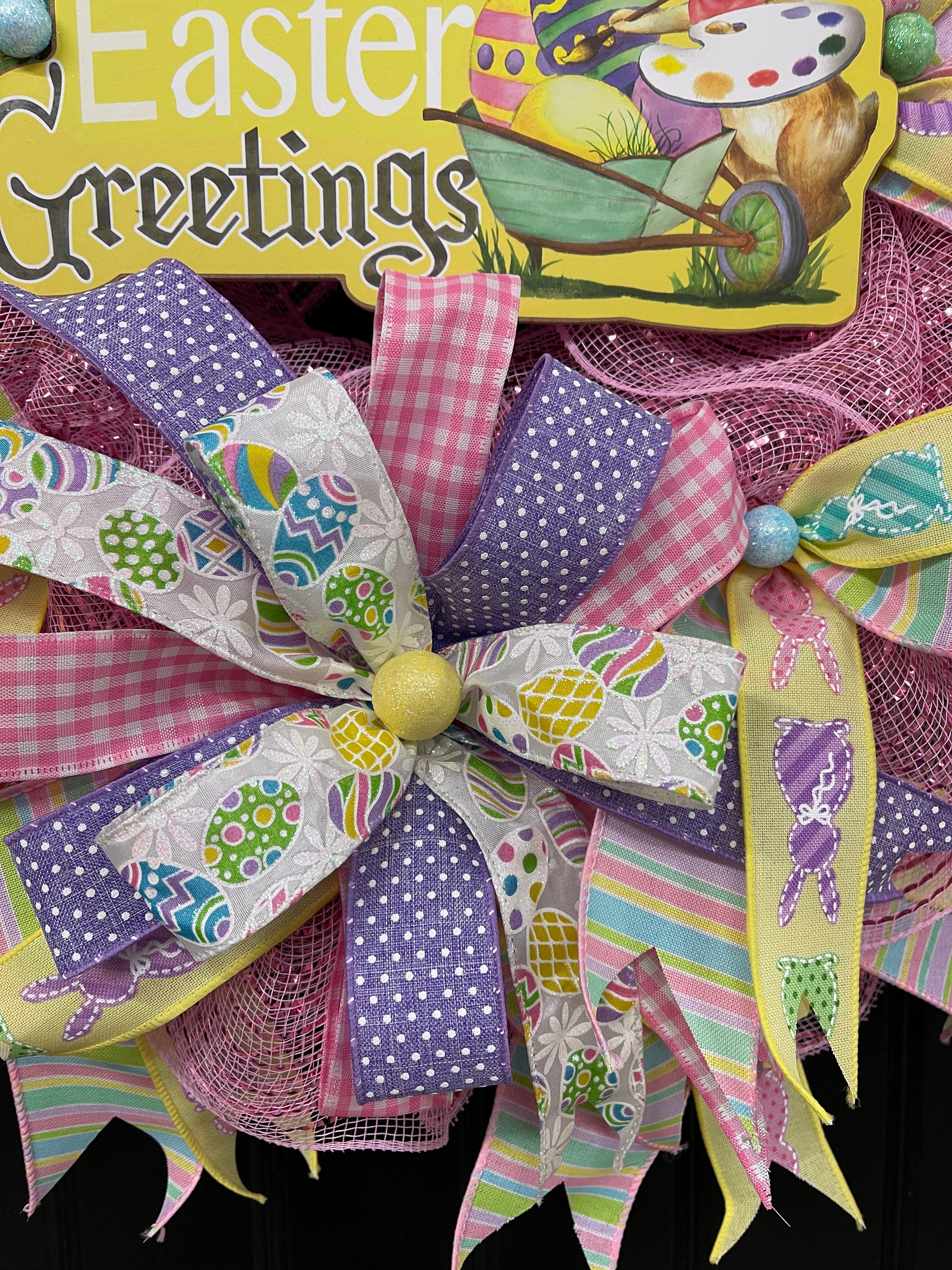 Close Up of Bow featuring Purple and White Polka Dot Ribbons, Pink and White Gingham Ribbons, Colored Pastel Eggs on White Ribbon and Pastel Bunnies on Yellow Ribbon