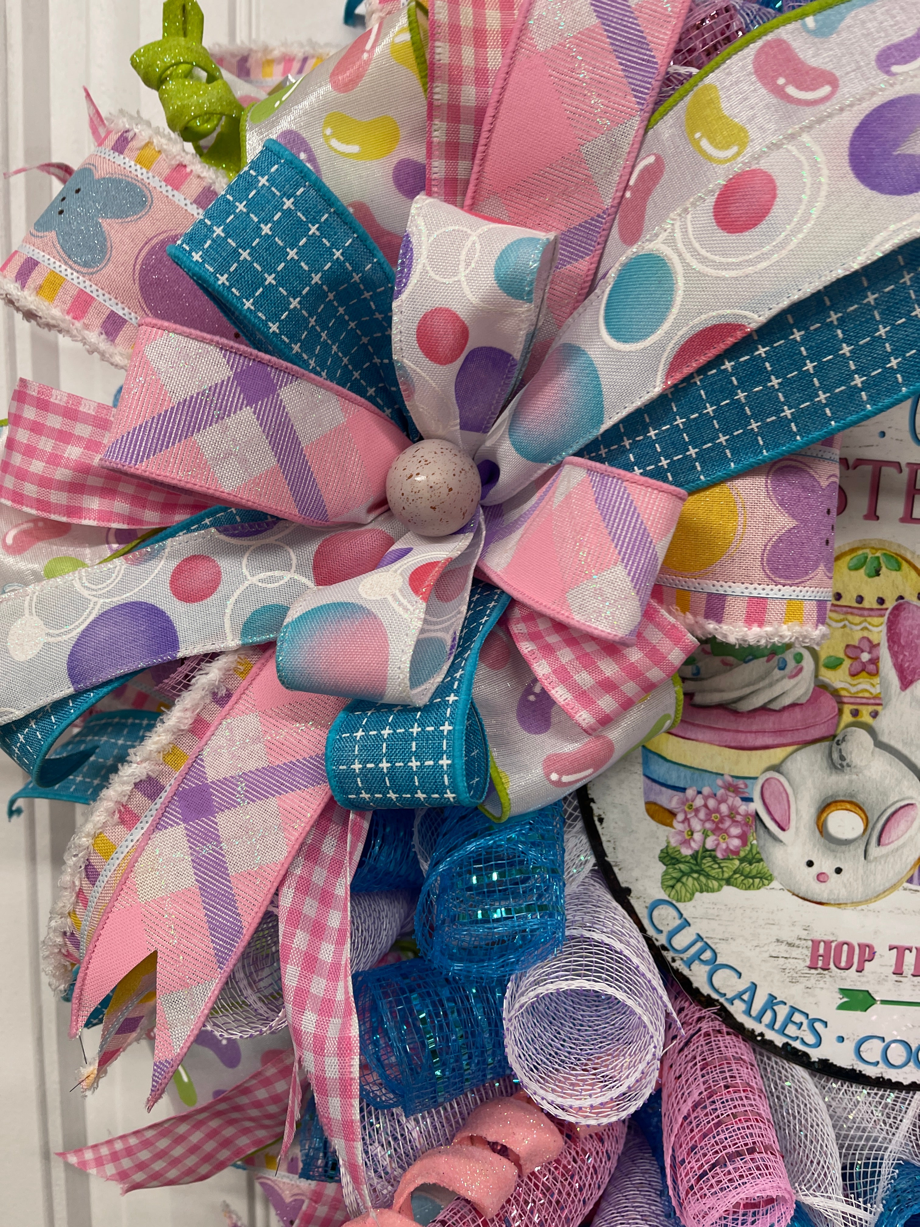 Close up of Bow on the wreath featuring Purple Speckled Egg in the center featuring Pink, Purple, Blue and White Ribbons