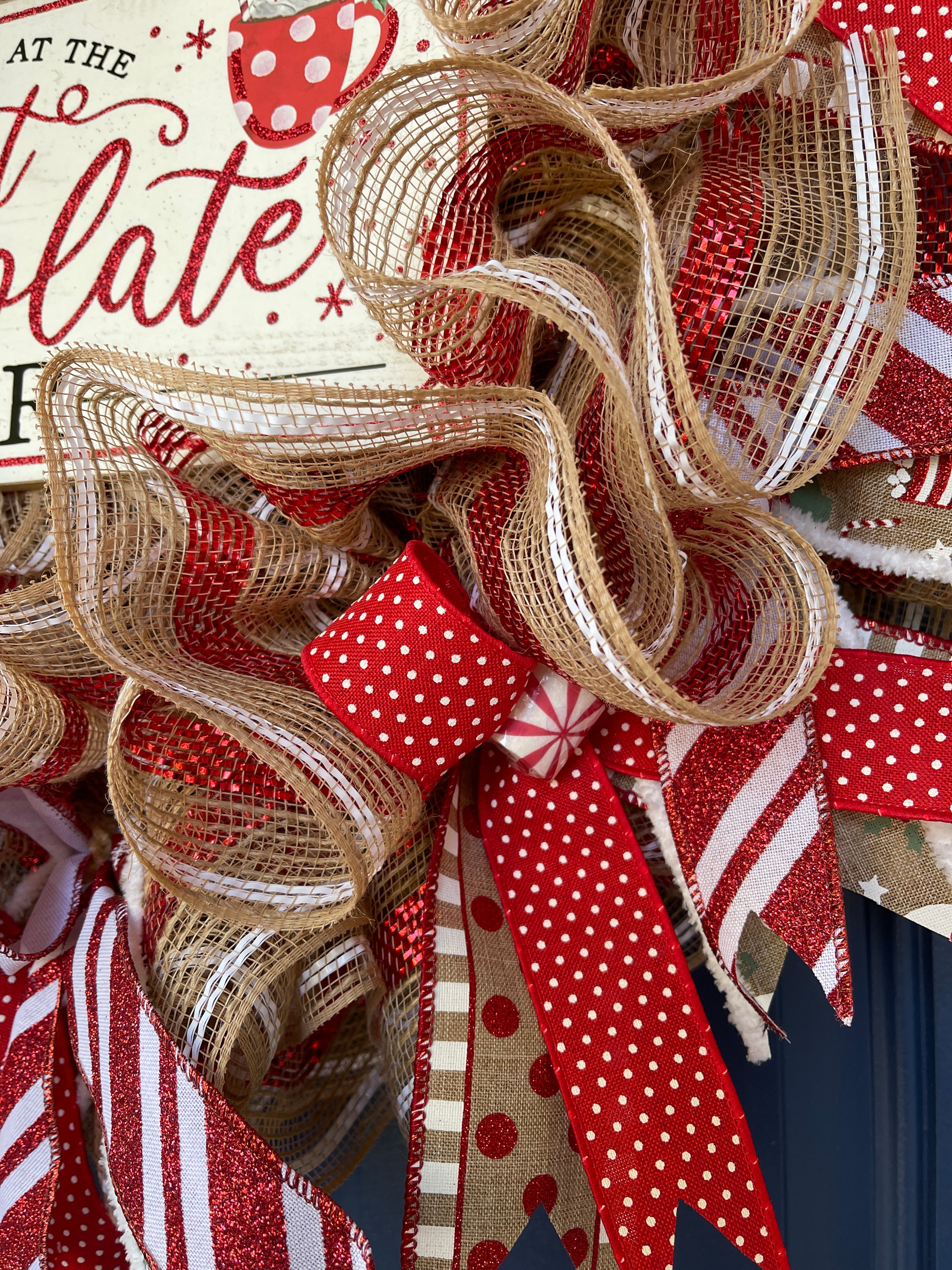 Close Up Detail on Hot Chocolate Bar Wreath featuring a red and white dot ribbon with a tan ribbon featuring red dots and white lines with a peppermint candy in the center. 