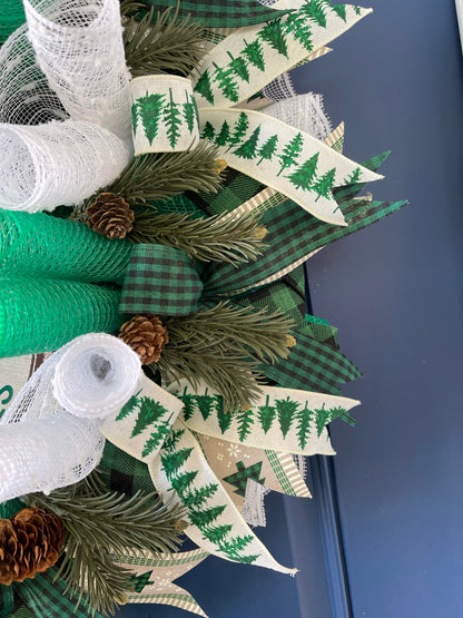 Close Up of Artificial Pine Sprigs with Pine Cones among Black, White and Green Ribbons on A Deco Mesh Wreath