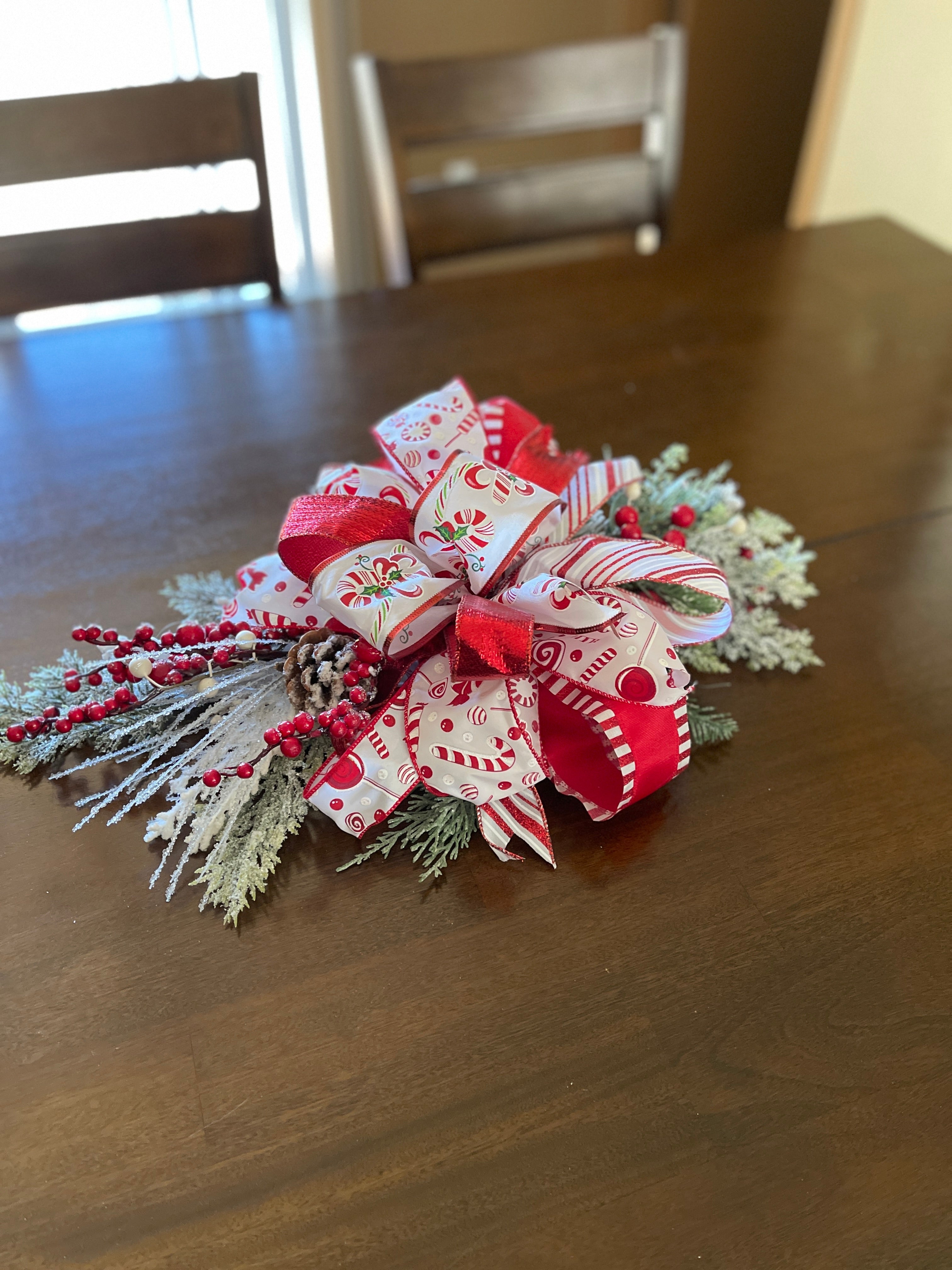 Red and White Candy Cane and Peppermint Lantern Swag with Evergreen Florals and Red Berries Used as a Centerpiece on a Table