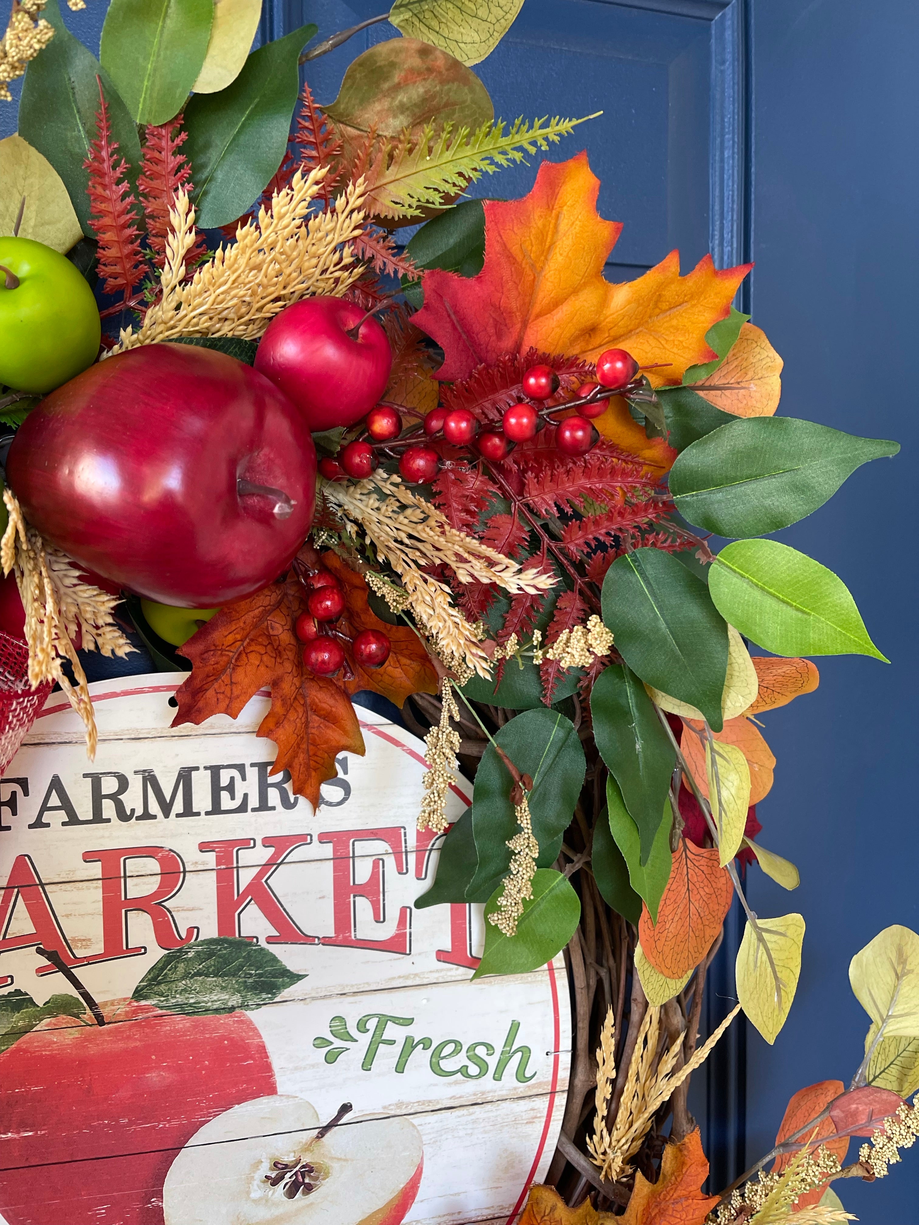 Close Up of Red and Green small and large apples, fall leaves, berries and Farmers Market Fresh Apple Sign on a wreath