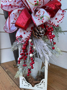 Close Up of Pinecones, Frosted Berries and Artificial Evergreens of Red and White Candy Cane and Peppermint Lantern Swag with Evergreen Florals and Red Berries. 