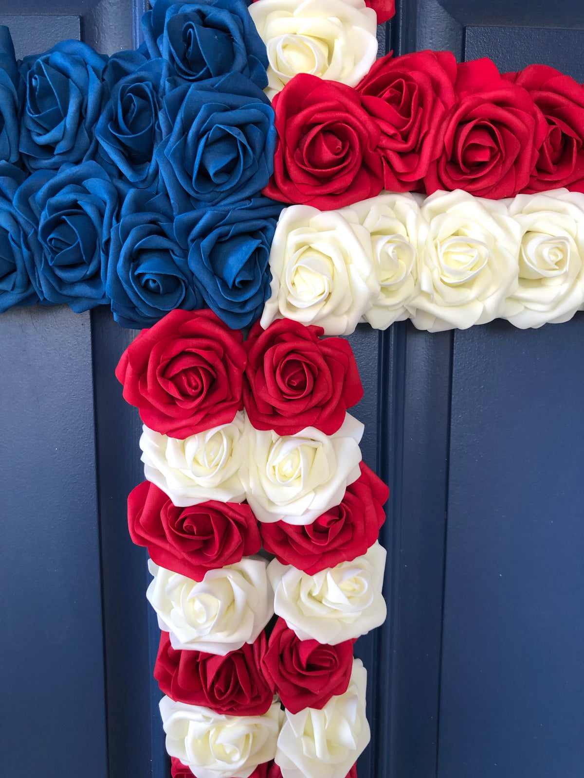 Red, White and Blue Roses in the shape of a cross on a blue door