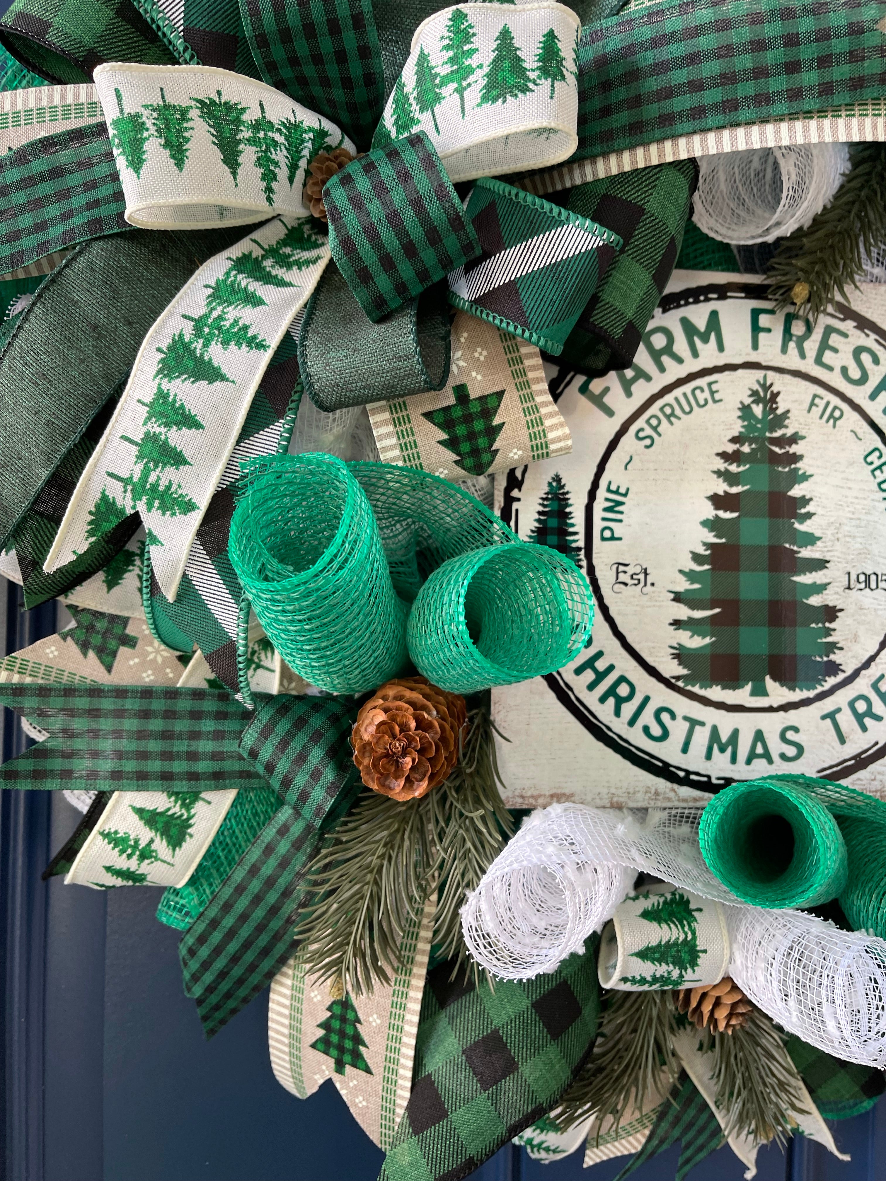 Close up of Farm Fresh Christmas Wreath featuring deco mesh curls of white and green, ribbons of black, white and green along with a Farm Fresh Christmas Tree sign, pine cones and artificial pine sprigs