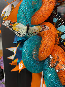Close Up Detail of curled teal and orange deco mesh with White Cream Butterfly