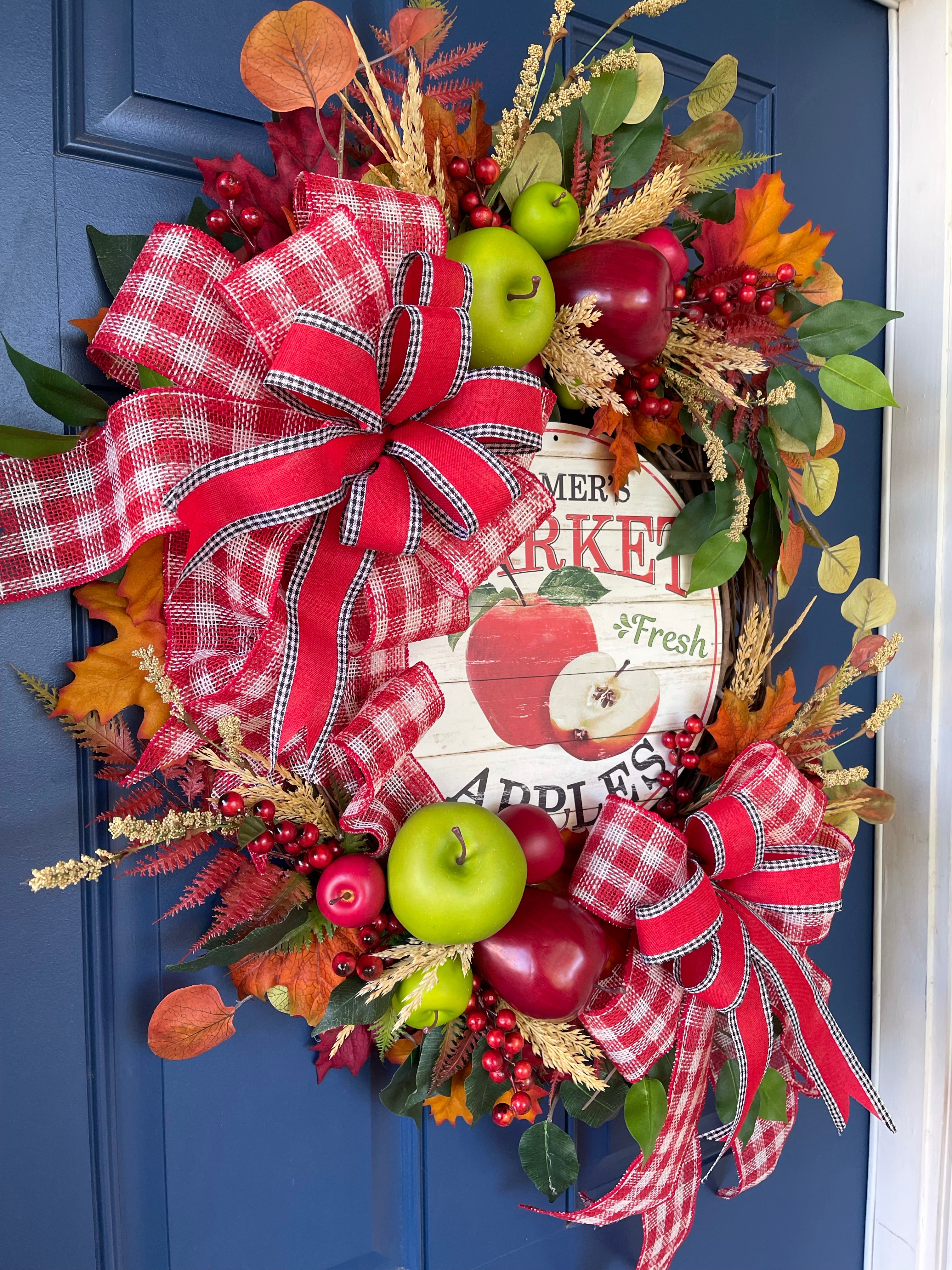 Left Side View of Fall Apple Grapevine Wreath filled with Red and Green Apples, Fall Leaves and Berries, Double Bows of Red, White and Black with a Farmers Market Fresh Apples Sign in the Center. 
