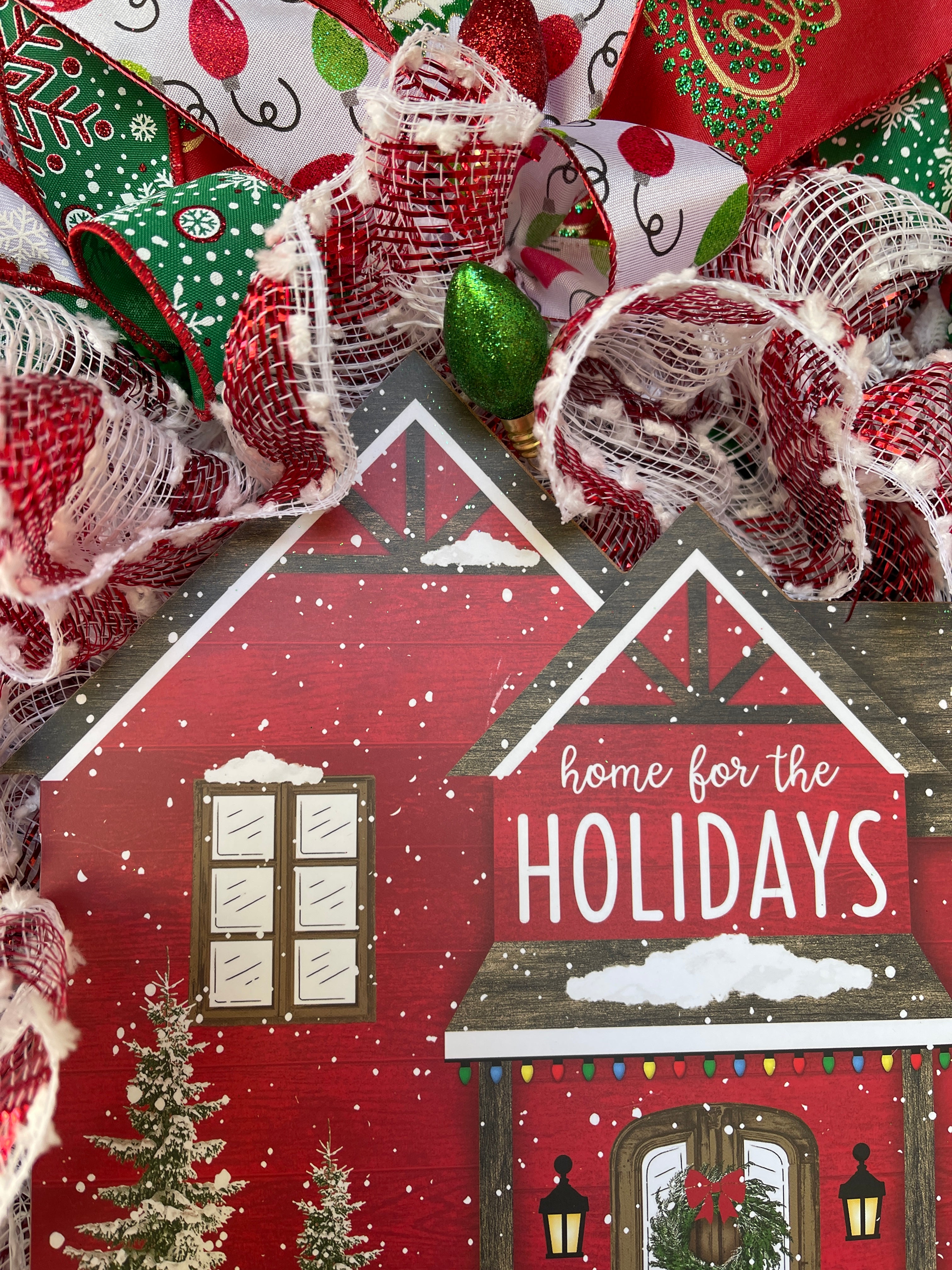 Close Up Details Around the House Shaped Home for the Holiday Sign featuring Red and White Snowball Deco Mesh and A Green Christmas Bulb