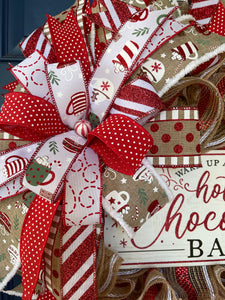 Close Up of Bow featuring ribbons of White, Red and Tan with cups of cocoa, red and white dots, red and white stripes and Tan ribbons with dots and lines with a round peppermint in the center. 