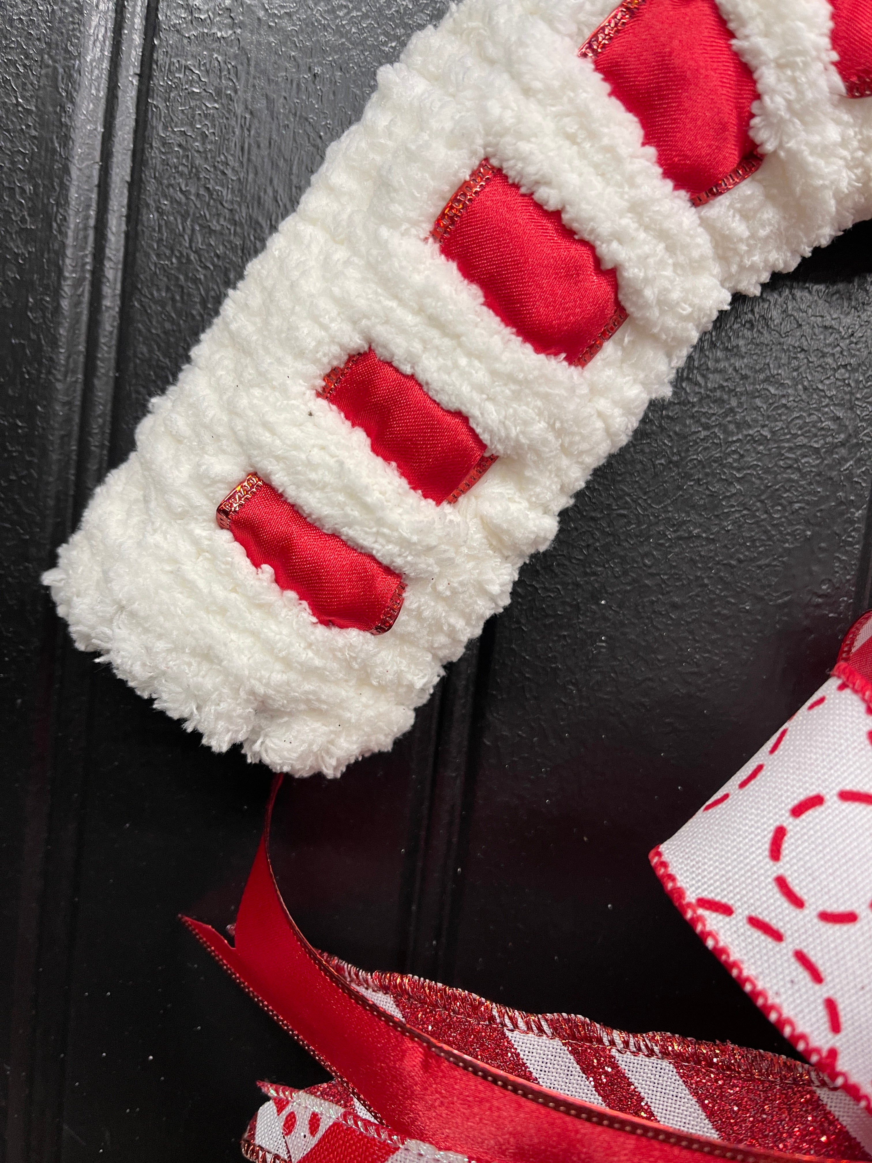 Close Up of  Red and White Candy Cane Chenille Yarn and Ribbon Christmas Wreath with Red and White Striped Bow for Front Door. 