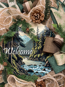 Close Up Detail of Round Sign with Welcome in White, with mountains, a bridge, a river and forest