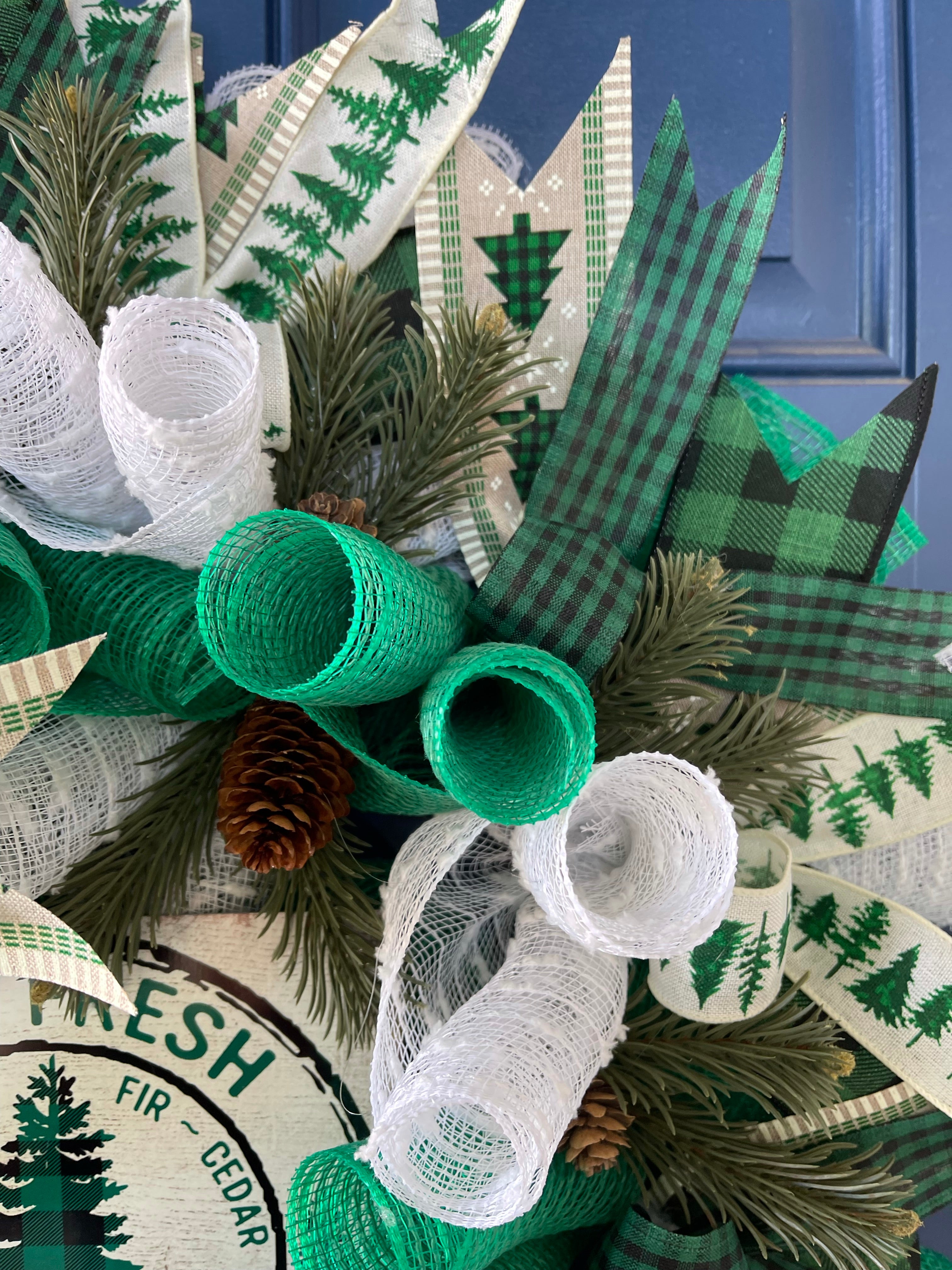 Close Up of Green and White Deco Mesh Curls with Black, White and Green Ribbon, Artificial Sprigs of Pine and Pine Cones.