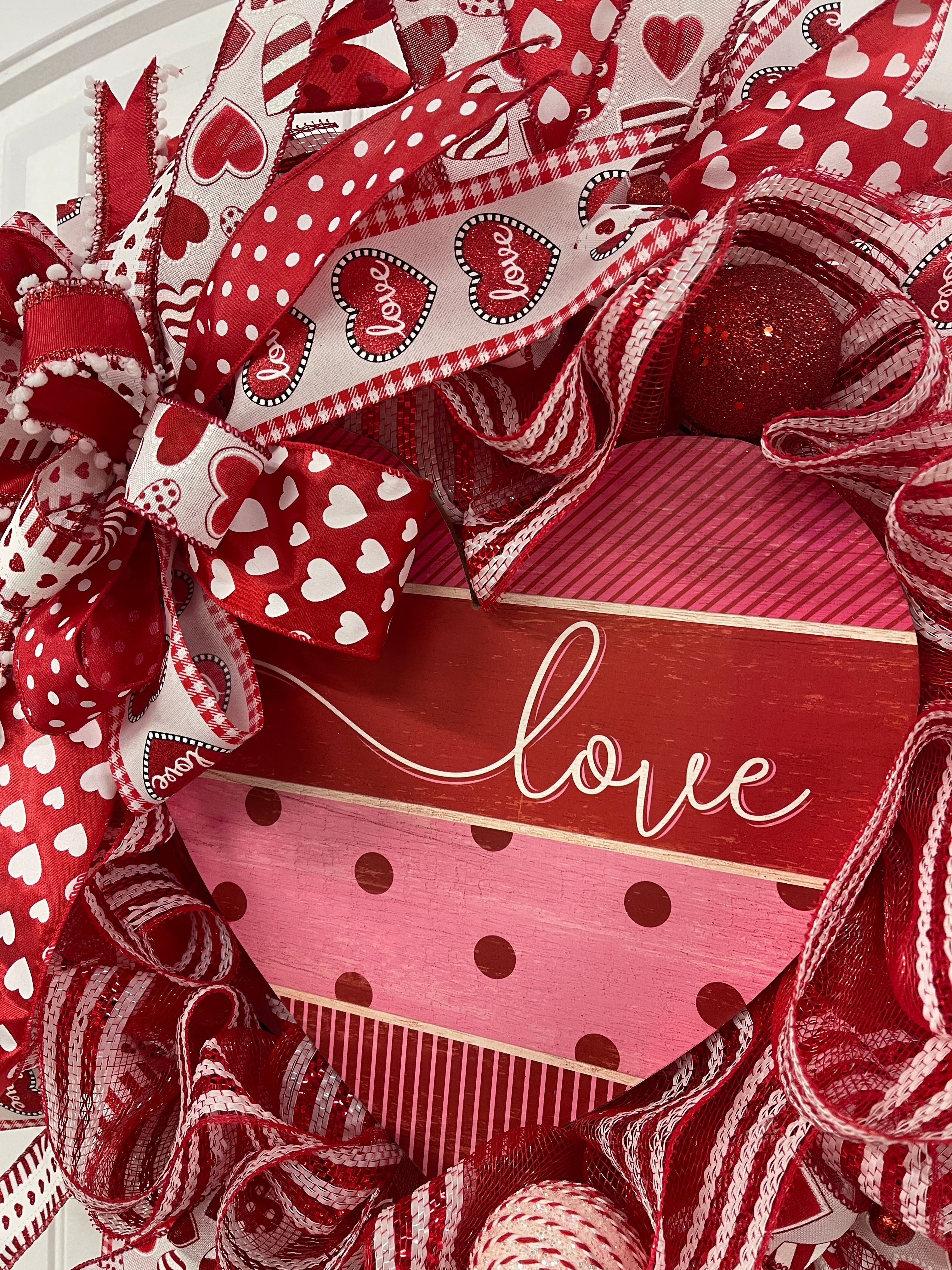 Close Up Detail of a Red and White Bow filled with Red, White and Black Ribbons, around a Heart Shaped Love Sign with large Red and White Balls