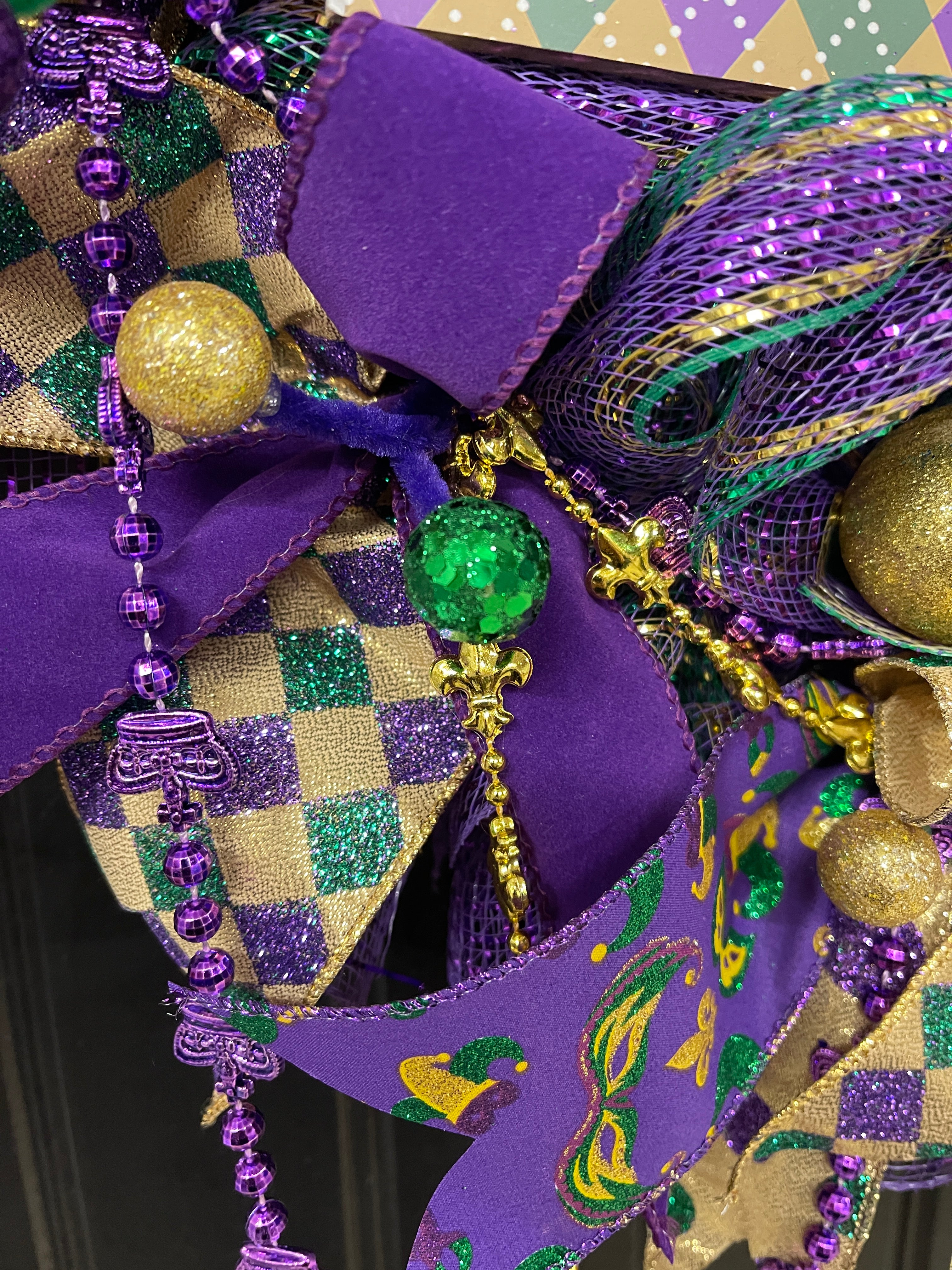 Close Up Detail of Green and Gold Glitter Balls with Purple and Gold Beads, Purple Velvet Ribbon, Purple and Green Harlequin Ribbon, Masks and Jester on Purple Ribbon