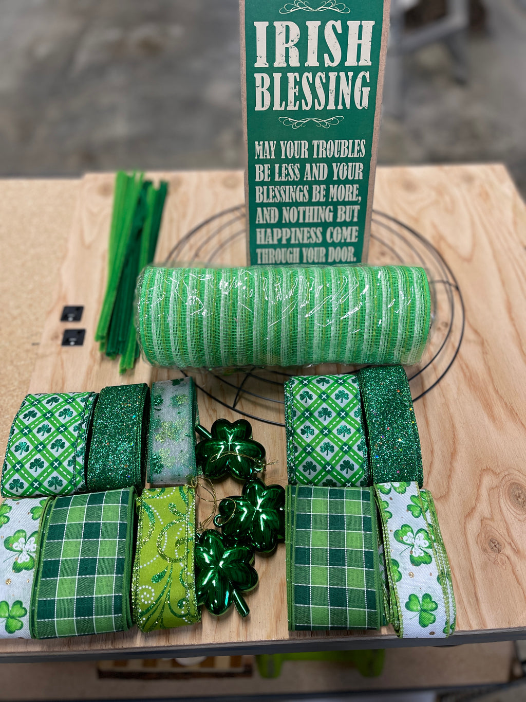 Irish Blessing Wreath Making Kit containing a roll of jute mesh in green and white stripes, lime green, white and green ribbons in clover patterns, solids and plaids