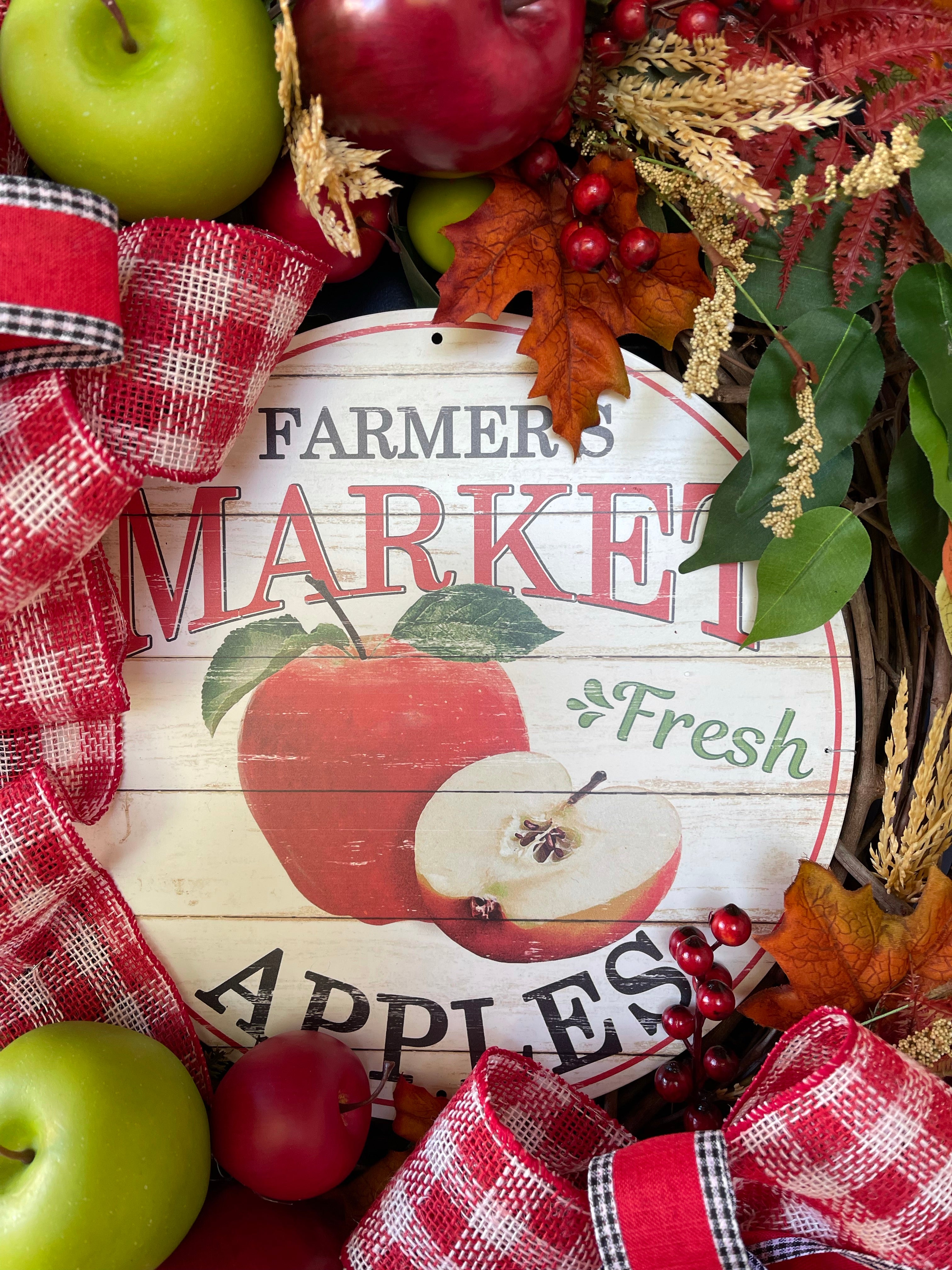 Close up on a Farmer's Market Fresh Apple Sign with a whole and sliced apple on the sign in red, black, white and green.