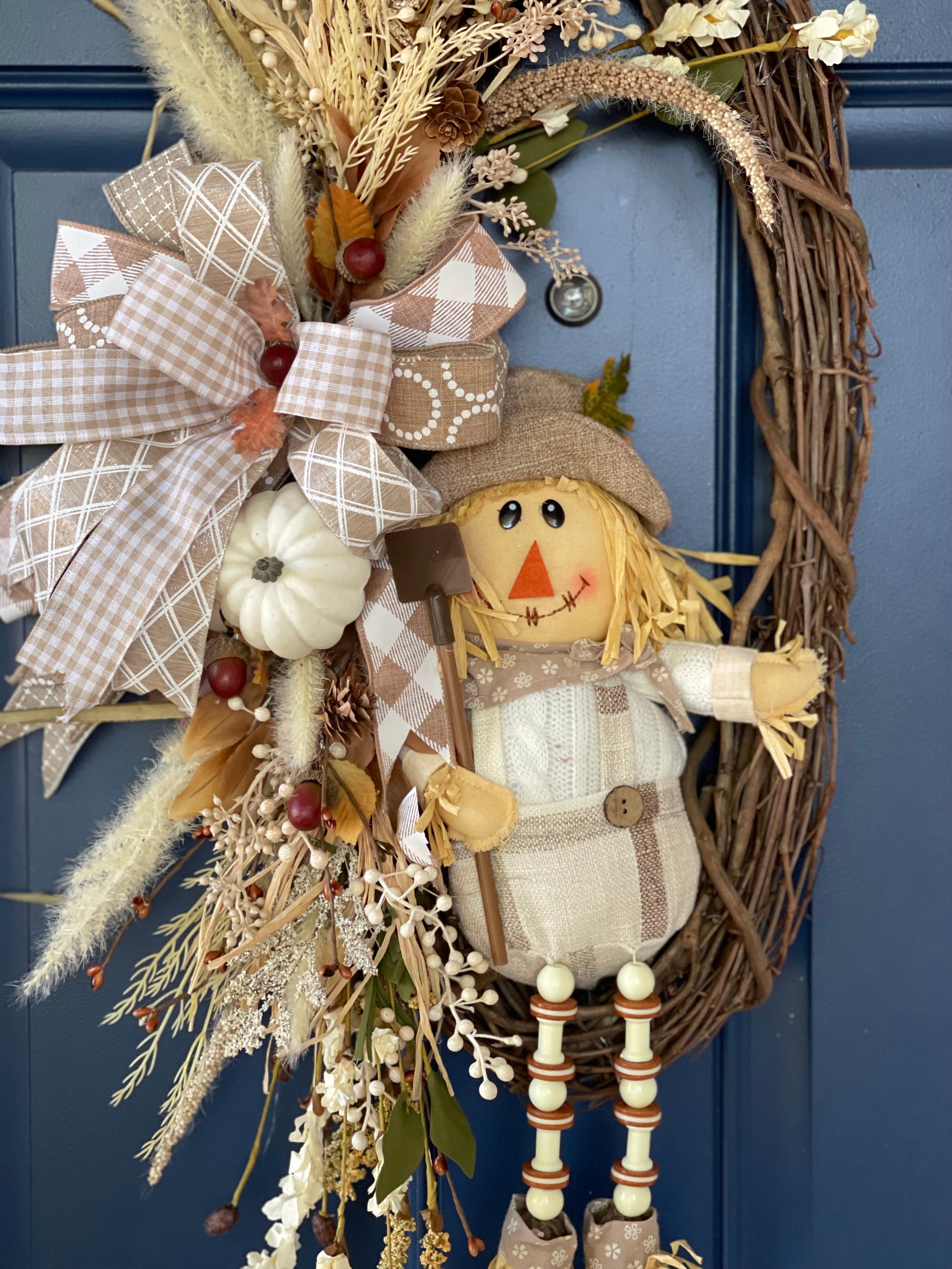 Plush Scarecrow with Shovel on a Grapevine wreath with White, Tan, and Light Brown Florals and Berries on a Blue Door