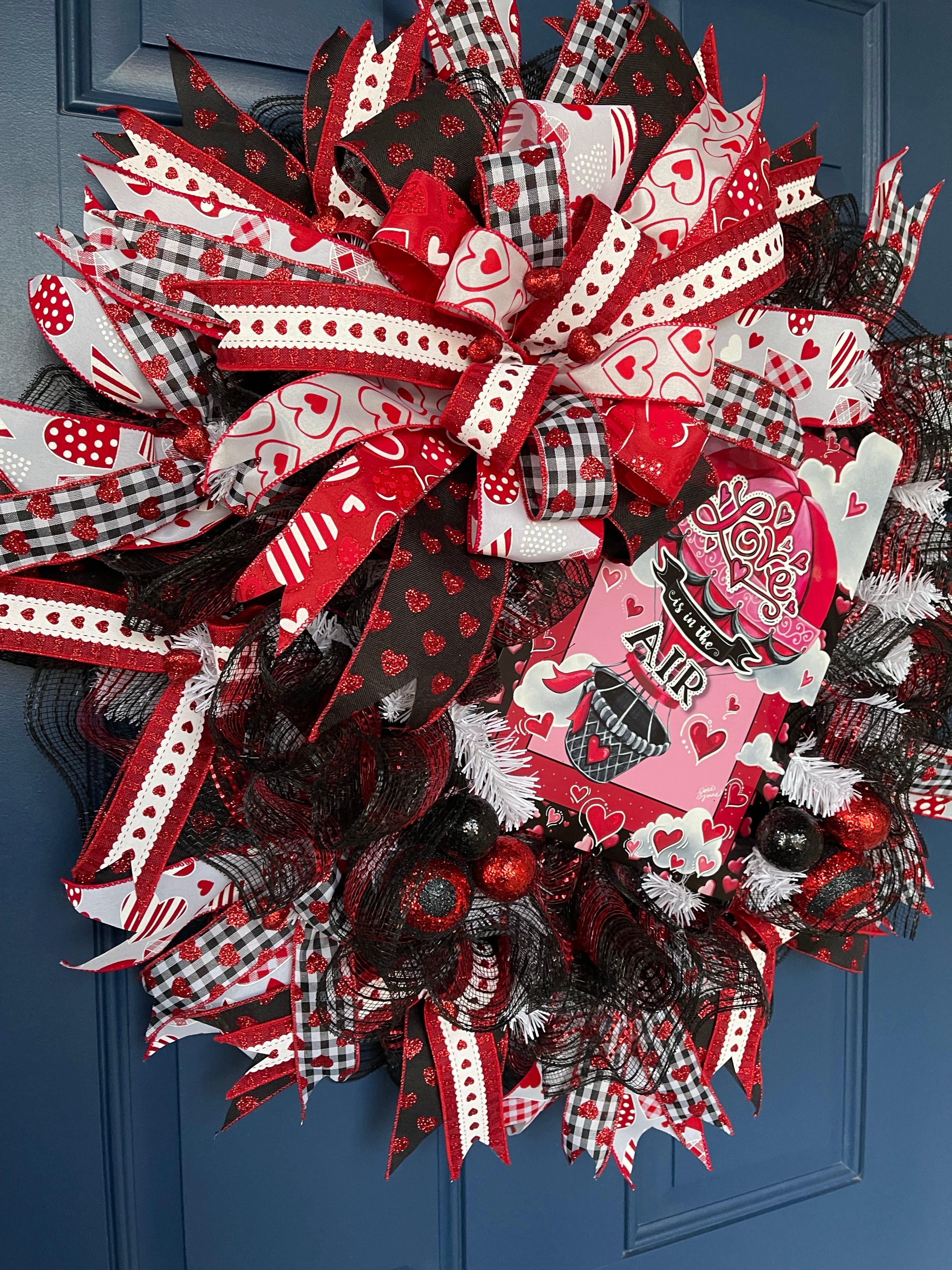 Left Side View of Red, White and Black Heart Filled Wreath with a Love its in the Air Hot Air Balloon sign on a Blue Door