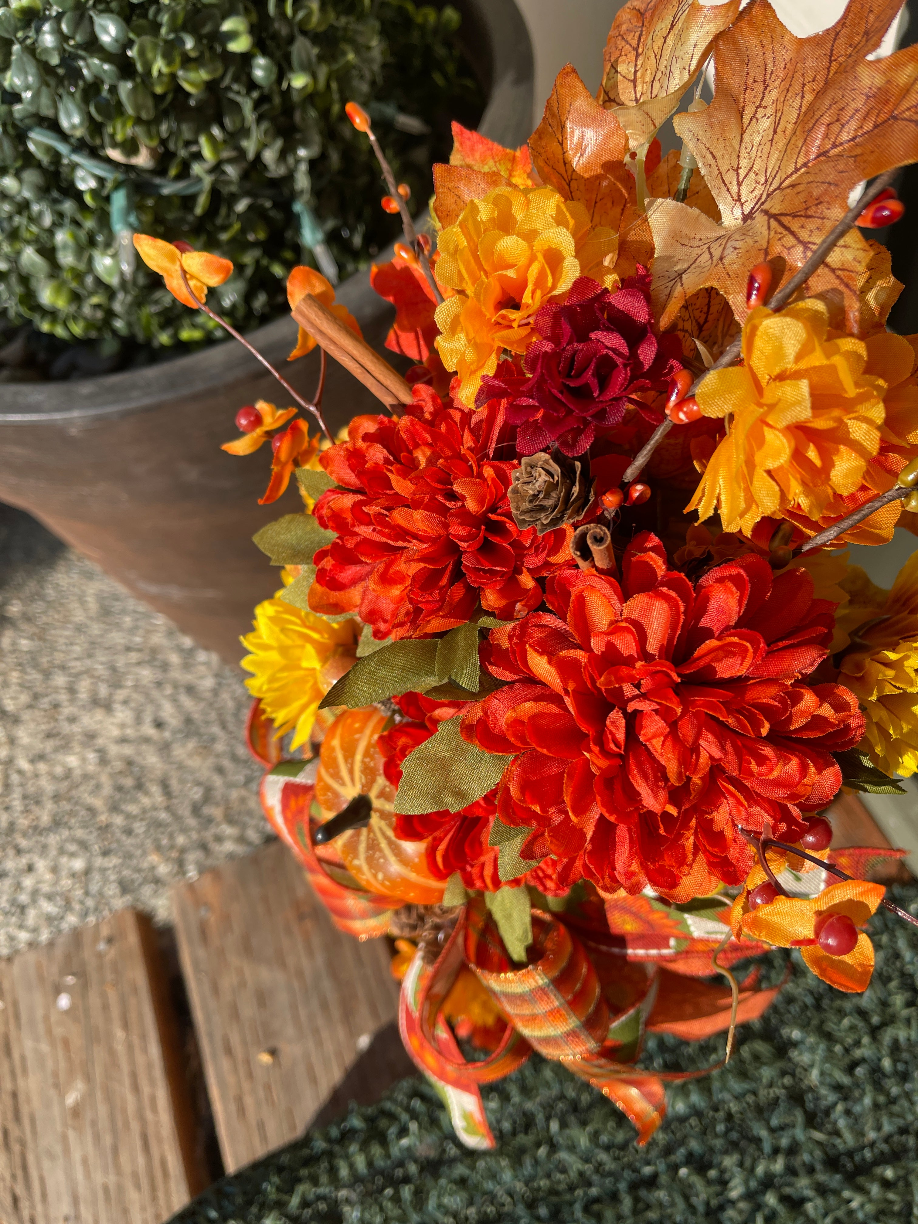 Close up Detail of Fall Leaves of Brown, Yellow and Orange, with Orange and Yellow Mums, Pumpkins , Cinnamon Sticks, Red Berries and Pine Cones on a White Lantern on the Porch