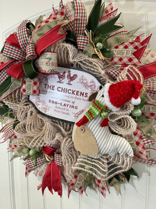 Right Side view of Red, White and Green Deco Mesh Christmas Chicken Wreath with Stuffed Chicken Wearing a Santa hat with Sign, The Chickens were nesting all snug in their beds while visions of egg laying danced in their heads.