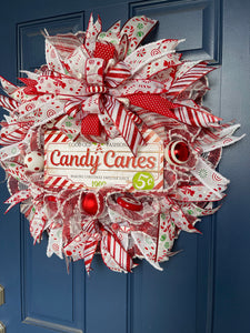 Candy cane Christmas wreath in white, red, and green accents seen hanging on door