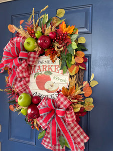 Right Side View of Fall Apple Grapevine Wreath filled with Red and Green Apples, Fall Leaves and Berries, Double Bows of Red, White and Black with a Farmers Market Fresh Apples Sign in the Center. 