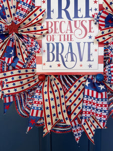 Close Up Detail of the Red, White and Blue Stars and Stripes Ribbons with Red Stars, Red and Blue Glitter Balls in the Center Surrounding a Land of the Free Because of the Brave Sign