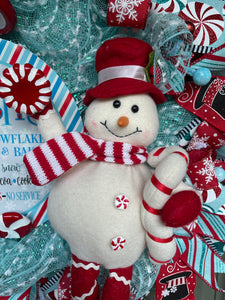 Close Up Detail of Snowman Plush wearing a red hat, Holding a Candy Cane and Peppermint Candy with a red and white striped scarf, peppermint candy buttons 